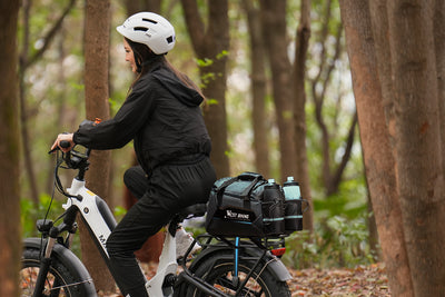 Woman riding Magicycle with West Biking black bike rack bag in a forest.