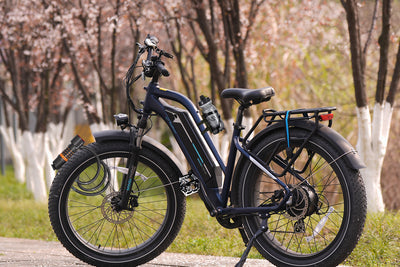 Electric fat tire bike with water bottle and phone mount beside blooming trees.