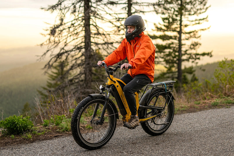 Rider on yellow Magicycle Deer ebike in orange jacket on forest trail