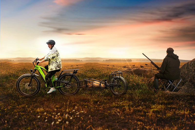 Magicycle Deer green ebike with trailer, rider in helmet on grassy terrain at sunset