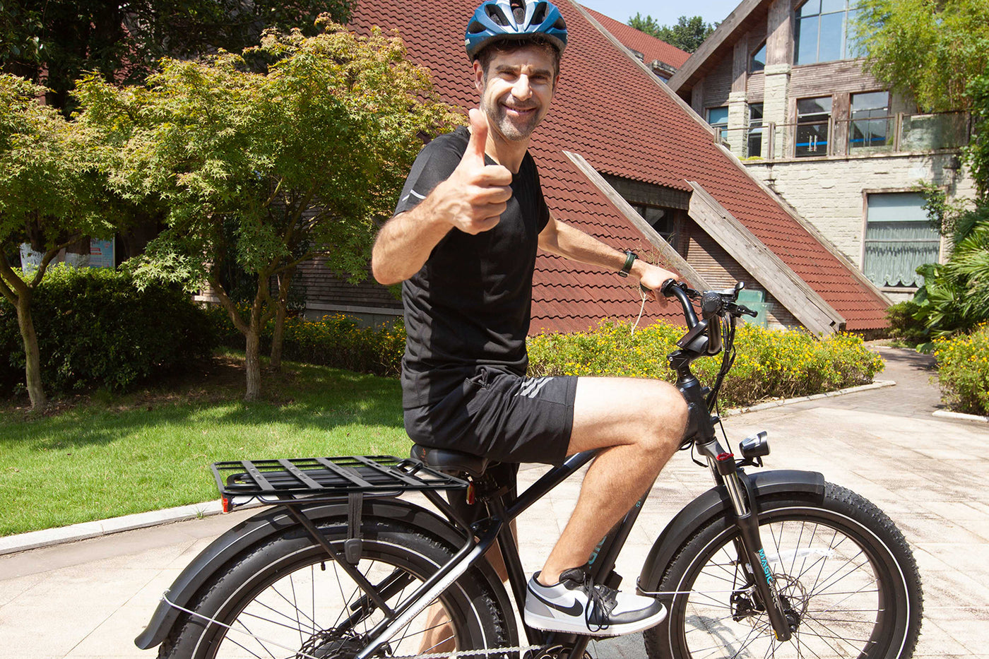 Person smiling and giving thumbs up on an ebike with cargo rack.