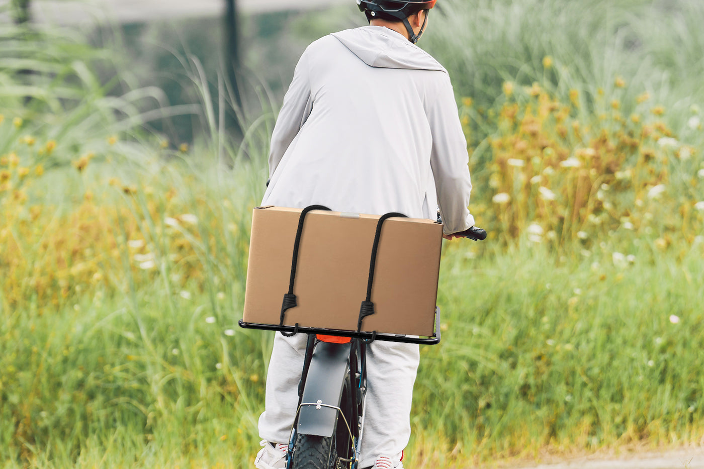 Ebike carrying large box on black aluminum platform rack for cargo transport.