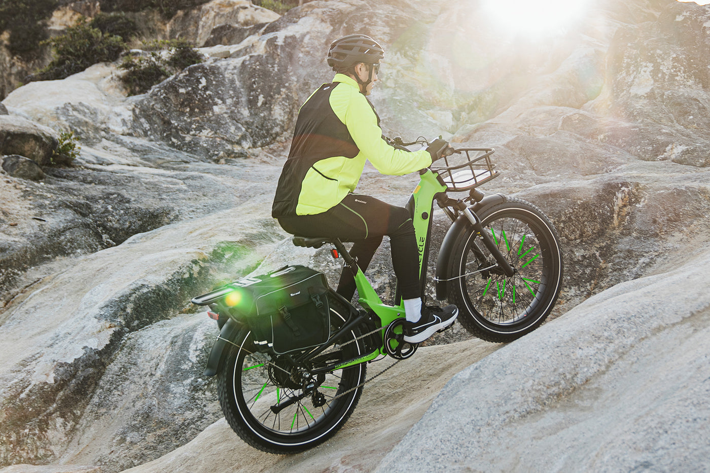 Rider on electric bike with green spoke reflectors navigating rocky terrain.